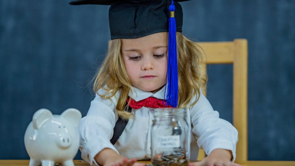little girl with graduation cap and piggy bank counting money